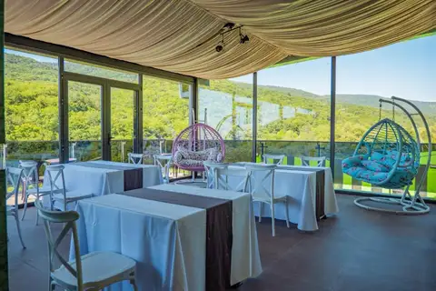 A terrace with hanging chairs and a forest view