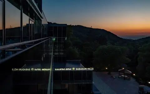 The hotel at dusk against forested hills